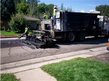 Picture shows construction truck spreading new asphalt on roadways during a street surfacing project